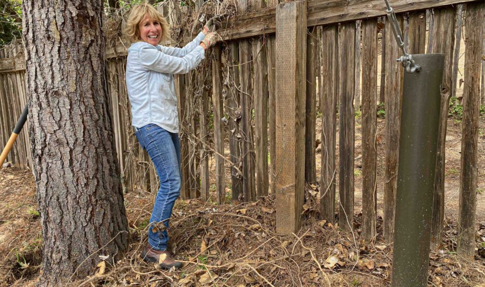 Cynthia pulling ivy off fence